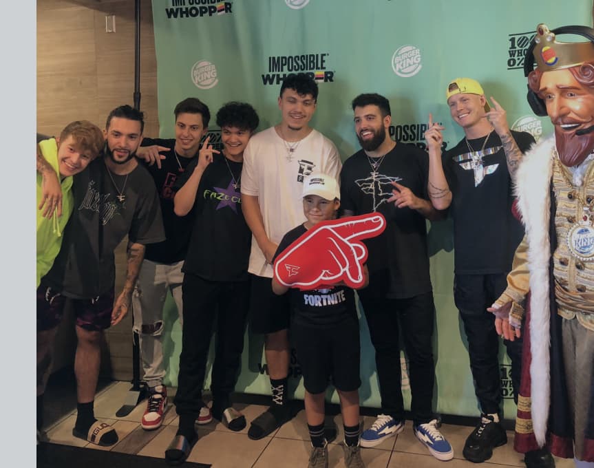 Burger King character and Faze Clan pose with little boy fan wearing giant foam finger for Impossible Whopper campaign
